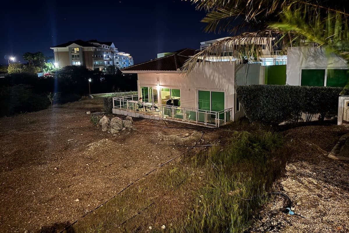 A building with a covered outdoor area, a paved path, and a small garden with rocks and plants.