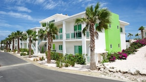 A modern multi-story hotel with balconies, palm trees, and a clear blue sky. - Piscadera Harbour Village (Willemstad)