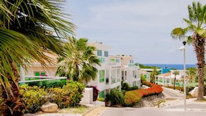 A coastal residential area with modern houses, palm trees, and a clear view of the sea. - Piscadera Harbour Village (Willemstad)
