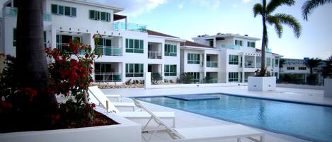 A modern hotel with a pool, white exterior, and balconies.