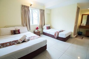 Une chambre d’hôtel avec deux lits, une fenêtre avec des rideaux, une table de chevet avec une lampe et une salle de bain avec un miroir et un lavabo.