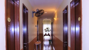 A hotel hallway with wooden doors, a ceiling fan, and a small table with potted plants. - Sun Inns Hotel Puchong (Puchong)