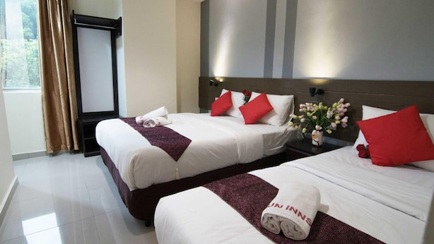 A hotel room with two beds, each with white linens and red pillows, a large window with curtains, and a wall-mounted TV. - Sun Inns Hotel Puchong (Puchong)