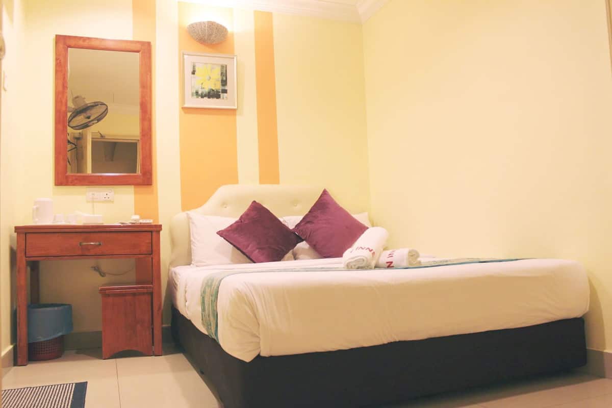 A bedroom with a bed, a bedside table, a mirror, and a wall-mounted picture.