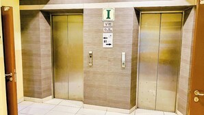 An elevator with a sign indicating it is the first floor, a no smoking sign, and a directional sign. - Sun Inns Hotel Puchong (Puchong)