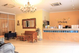 A hotel reception area with a reception desk, a chandelier, a mirror, and seating arrangements.