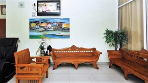 A living room with a wooden sofa, a wooden table, and chairs. There is a painting on the wall and a television mounted above it. - Sun Inns Hotel Puchong (Puchong)