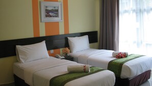 Een hotelkamer met twee bedden, een nachtkastje, een lijst met een afbeelding en een raam met gordijnen.