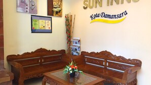 A reception area with two wooden sofas, a glass coffee table, and a wall displaying the Sun Inns logo and a certificate. - Sun Inns Hotel Kota Damansara (Petaling Jaya)