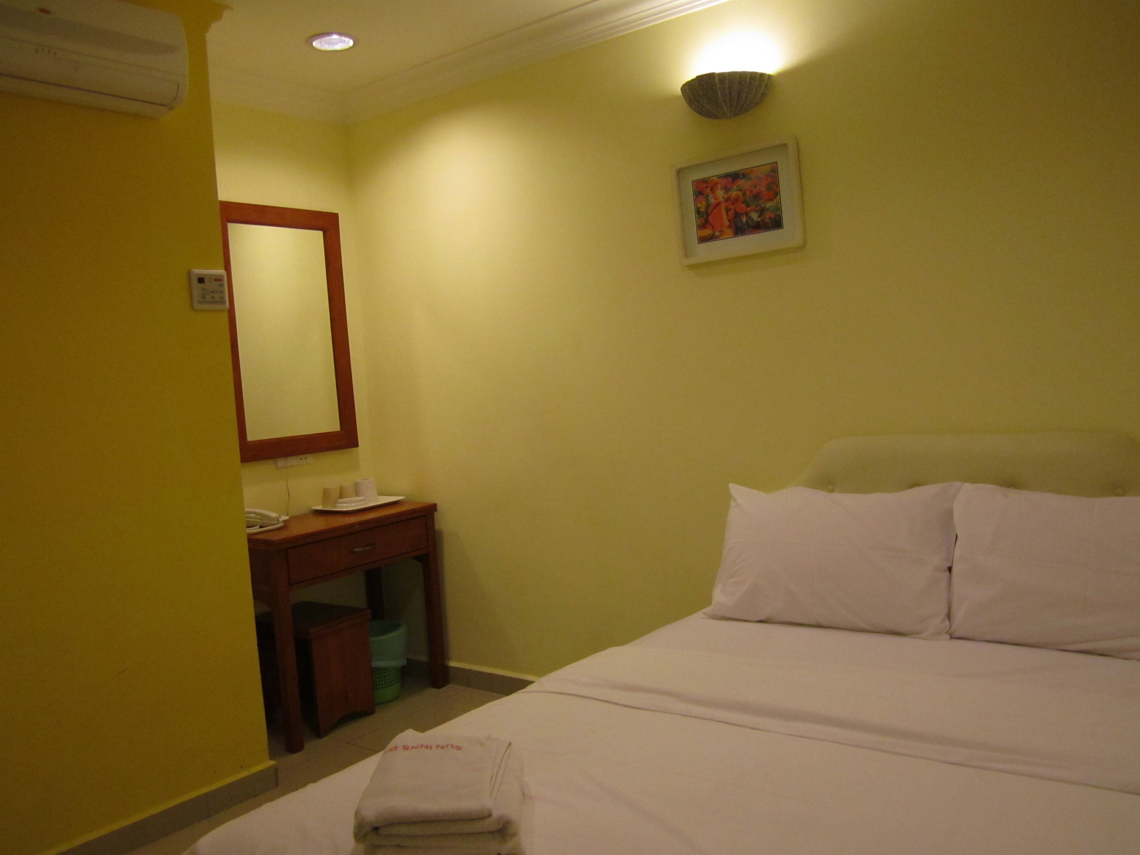 Ein Hotelzimmer mit einem Bett, einem Nachttisch mit Lampe, einem Spiegel und einem Wandbild.