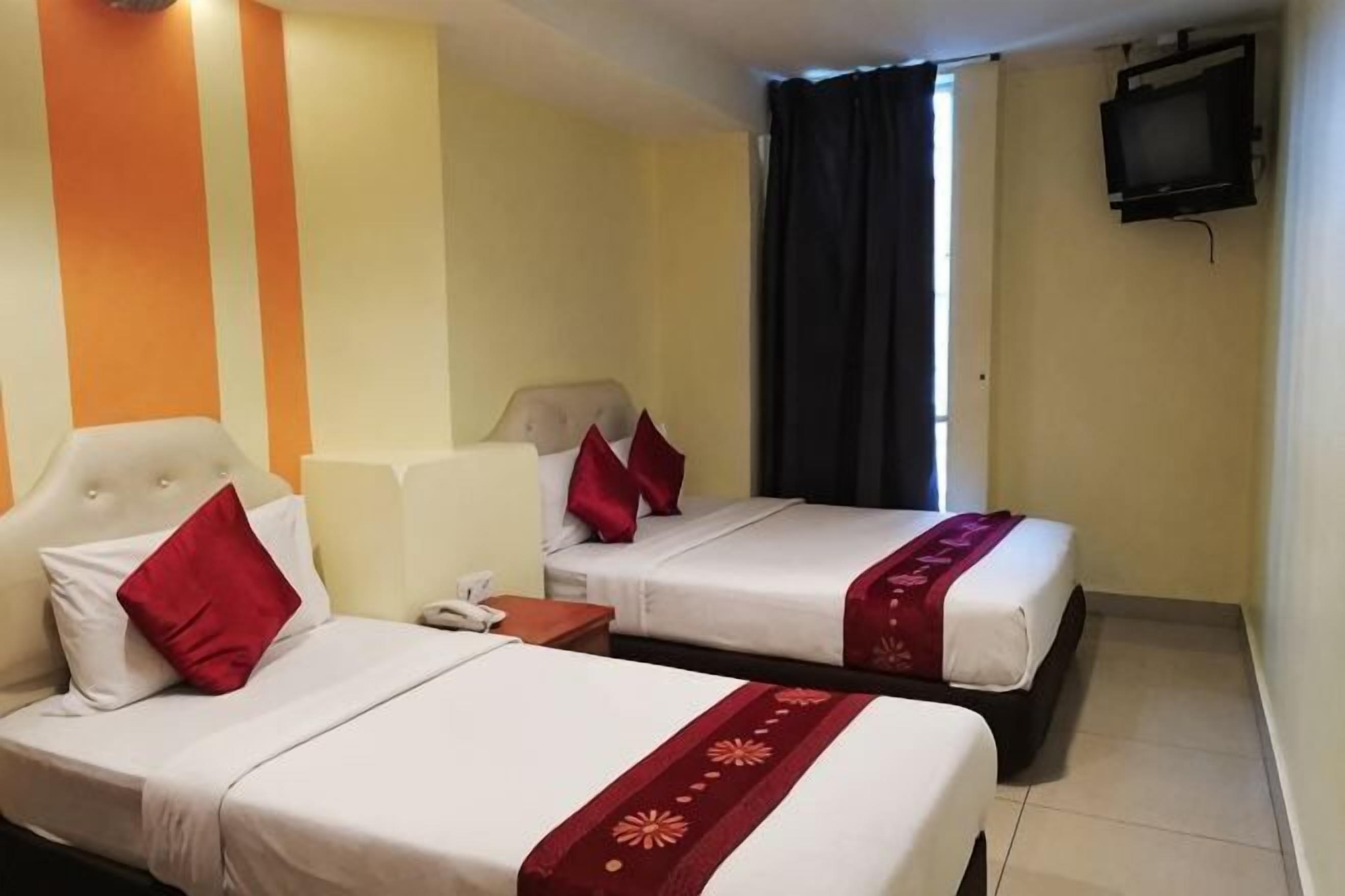 Een hotelkamer met twee bedden, een televisie en een raam met gordijnen.