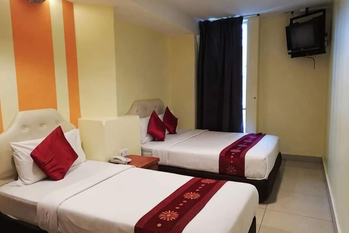 A hotel room with two beds, a TV, and a window with curtains.