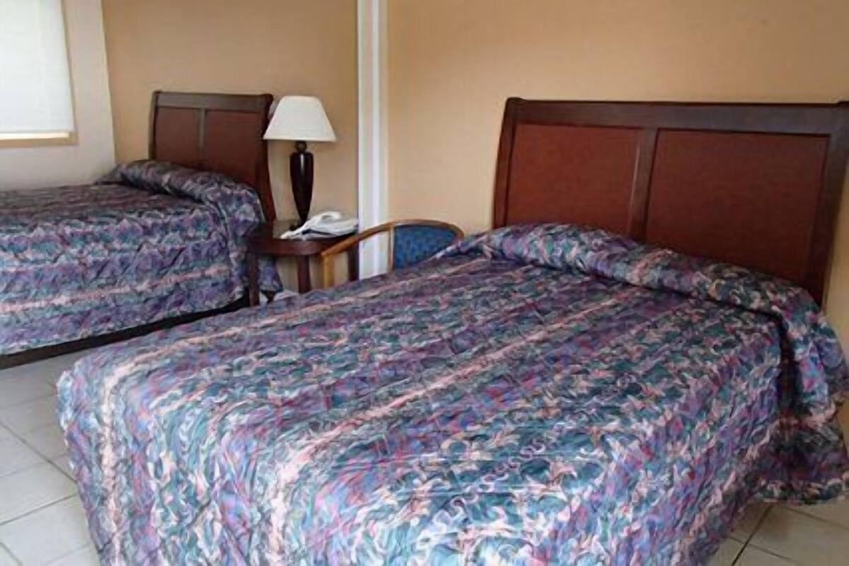 Two twin beds with floral bedding, a bedside table with a lamp, and a chair.