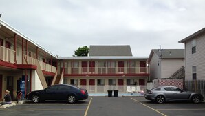 A motel with a two-story building, a parking lot, and a fenced area with chairs.