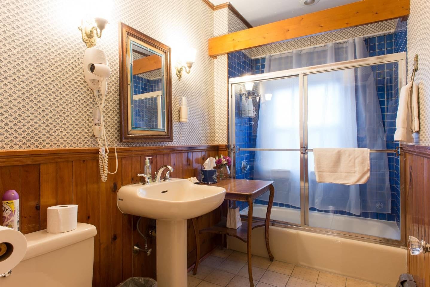 A bathroom with a wooden vanity, a sink, a mirror, a shower with a glass door, and a towel rack.