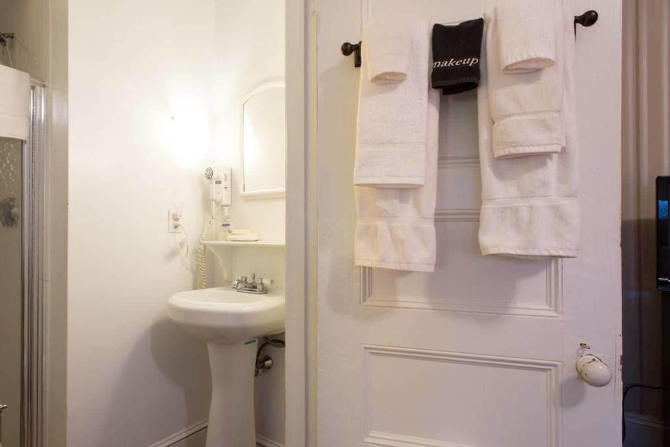 A bathroom with a white sink, a mirror, and a towel rack with a 'makeup' towel.
