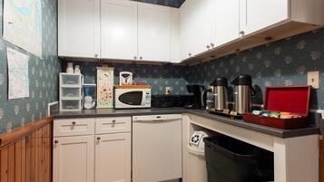A kitchen with white cabinets, a microwave, a coffee maker, and a red box on the counter.