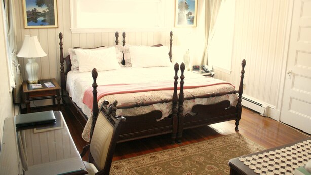 A traditional bedroom with a four-poster bed, a bedside table with a lamp, and a nightstand.
