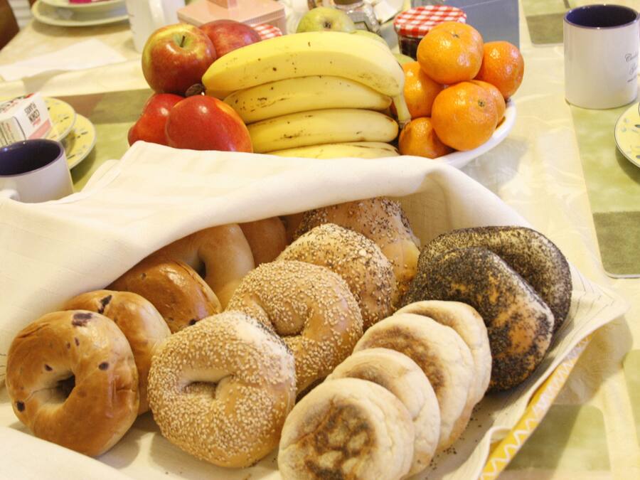 A table with a variety of food items including fruits, bagels, and a coffee cup.