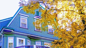 A two-story house with a wrap-around porch, a stone archway, and a staircase leading to the entrance. - Coolidge Corner Guest House (Brookline)