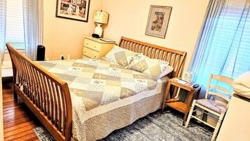 A bedroom with a wooden bed, a nightstand, a chair, and a bedside table.