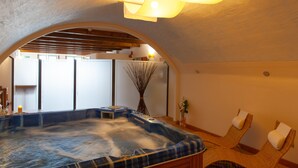 Un área de spa con un jacuzzi, sillas de mimbre y una lámpara en el techo.