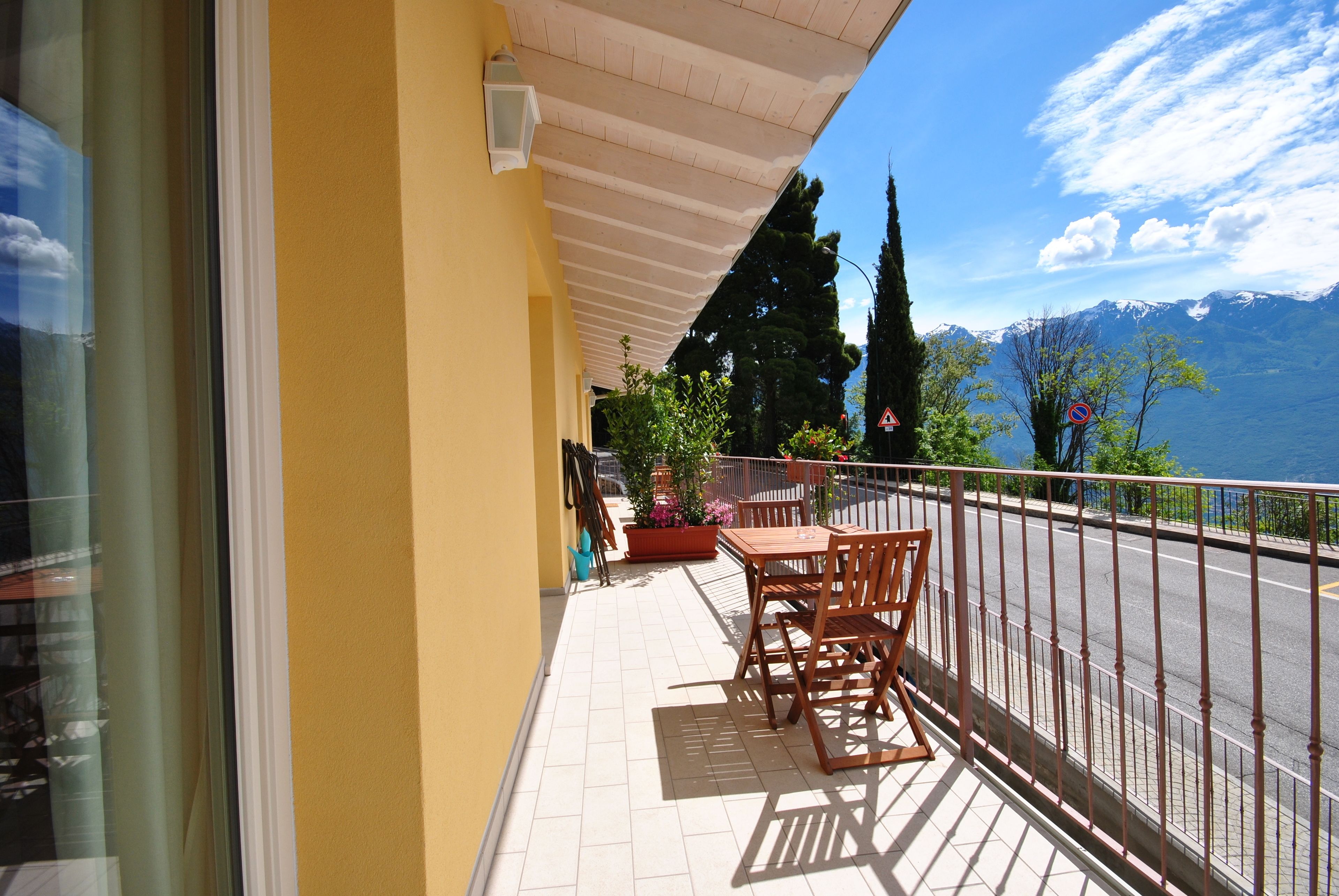 Un balcon avec une table et des chaises, un pot de fleurs et une vue sur une chaîne de montagnes.