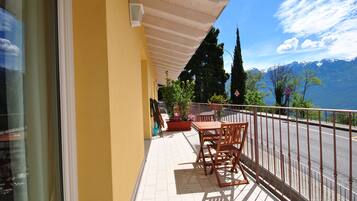 Un balcon avec une table et des chaises, un pot de fleurs et une vue sur une chaîne de montagnes.