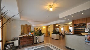 Un hall de hotel con mostrador de recepción, chimenea, espejo y cafetera.
