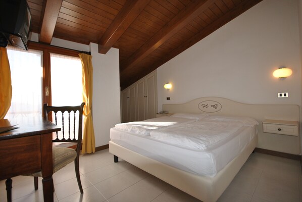 A bedroom with a wooden ceiling, a bed, a nightstand, a chair, and a window with curtains.