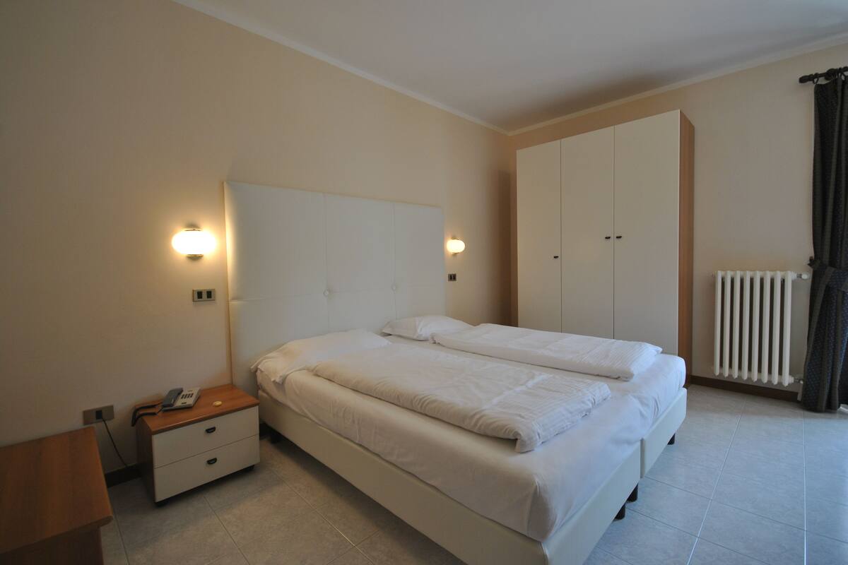 Un dormitorio con una cama grande, una mesita de noche, un armario y un radiador.