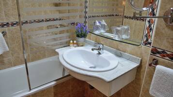 Un baño con un lavamanos blanco, cabina de ducha con mampara de vidrio y un espejo.