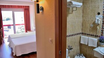 Une chambre d’hôtel avec un lit, une salle de bain comprenant un lavabo et des toilettes, et un balcon avec vue.