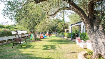 Relax in a serene outdoor space with a hammock swing and a play area for kids, surrounded by a shaded gazebo.
