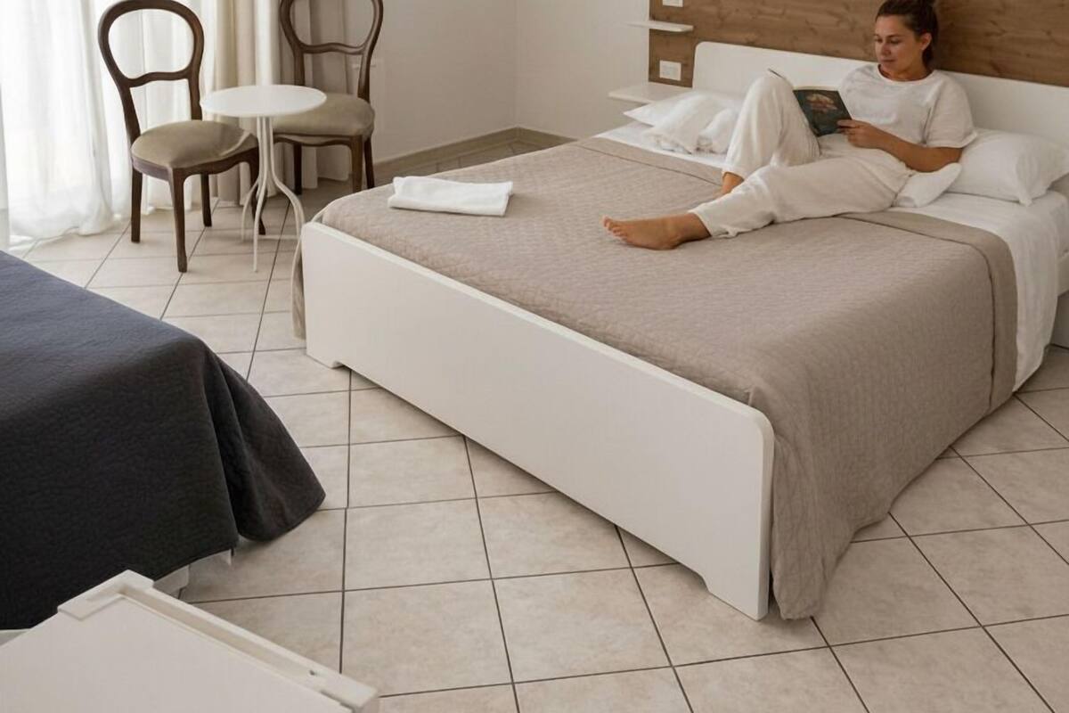 Une chambre d’hôtel avec un lit, une chaise, une petite table et une fenêtre avec des rideaux.