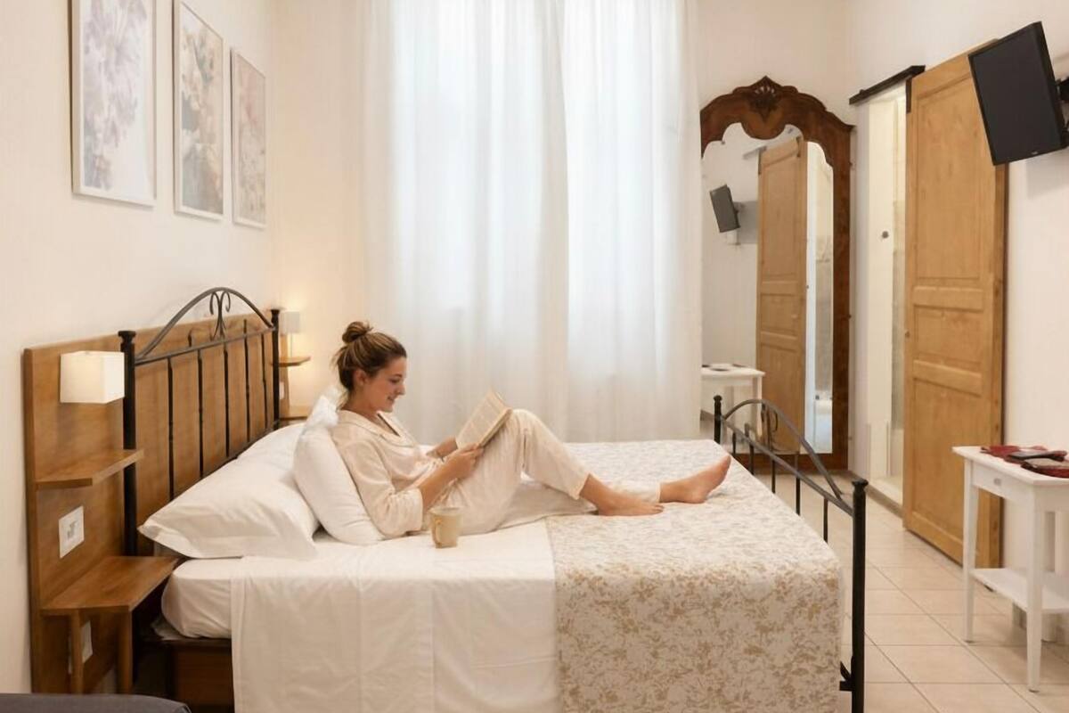 Une chambre à coucher avec un lit, une table de chevet avec une lampe, une chaise, un téléviseur et une armoire.