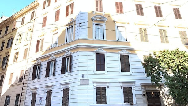 Ein mehrgeschossiges Gebäude mit Hauseingang an der Ecke, großen Fenstern und einer sichtbaren Tür.