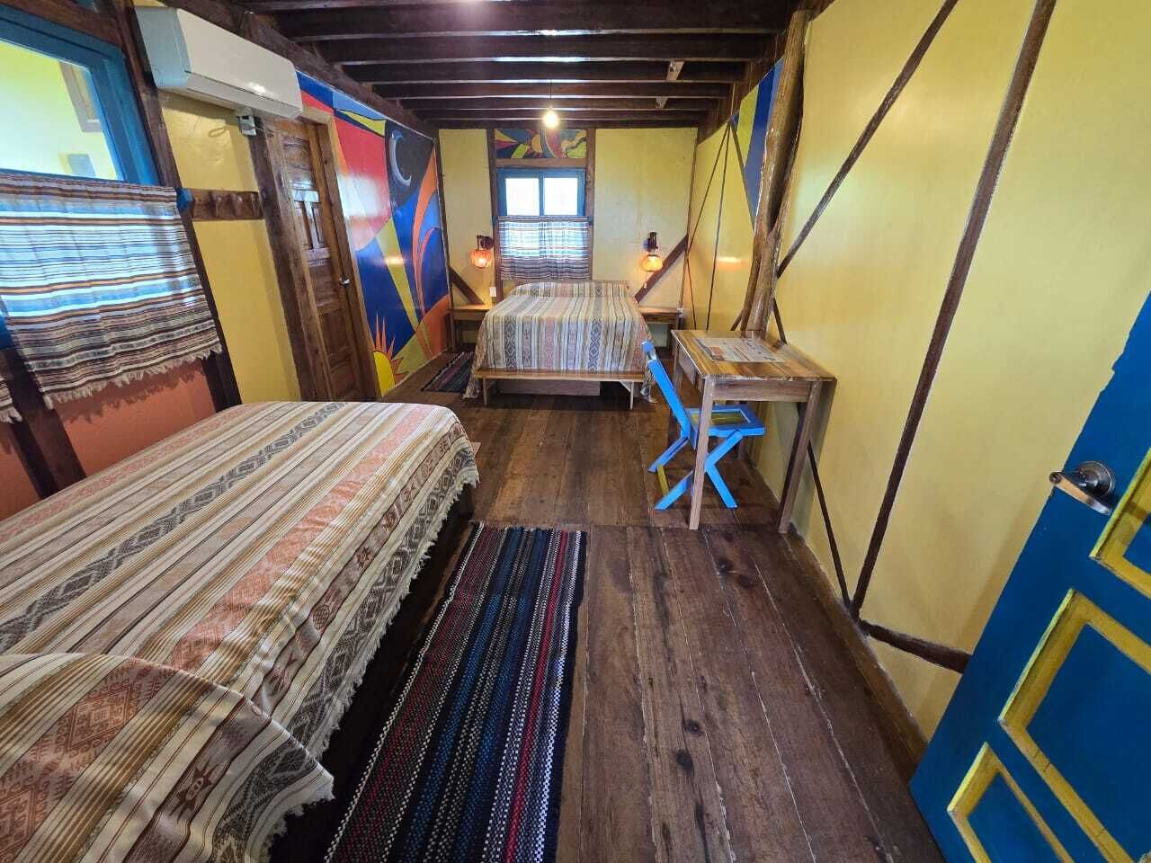A room with two beds, a small table, and a window.