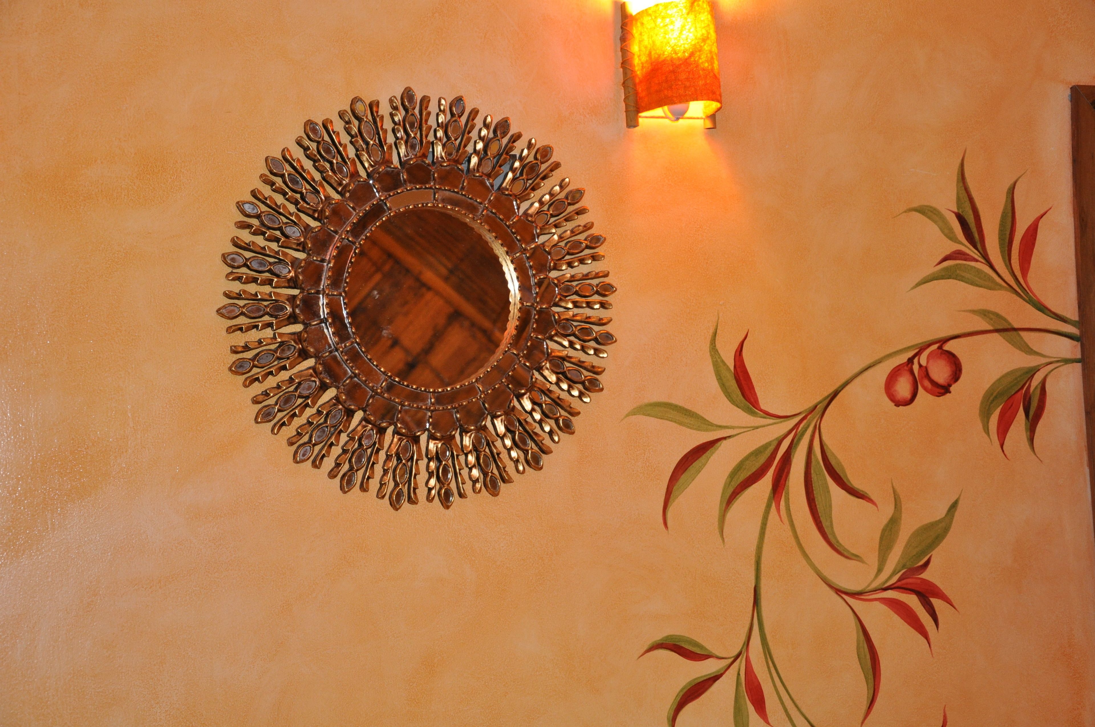 A wall with a decorative mirror and a floral mural.