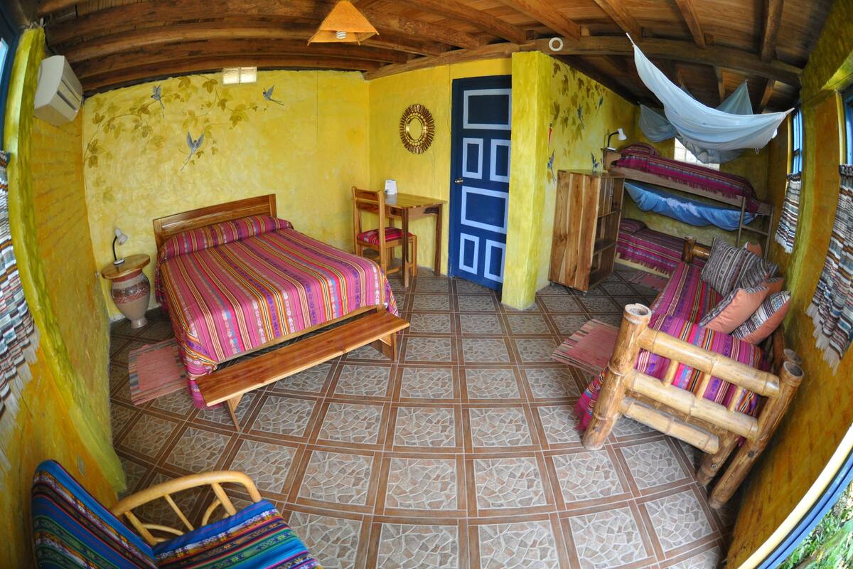 A room with a bed, a chair, a table, and a door.