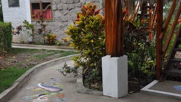 A courtyard with a mosaic floor design, a stone wall, and a wooden pergola.