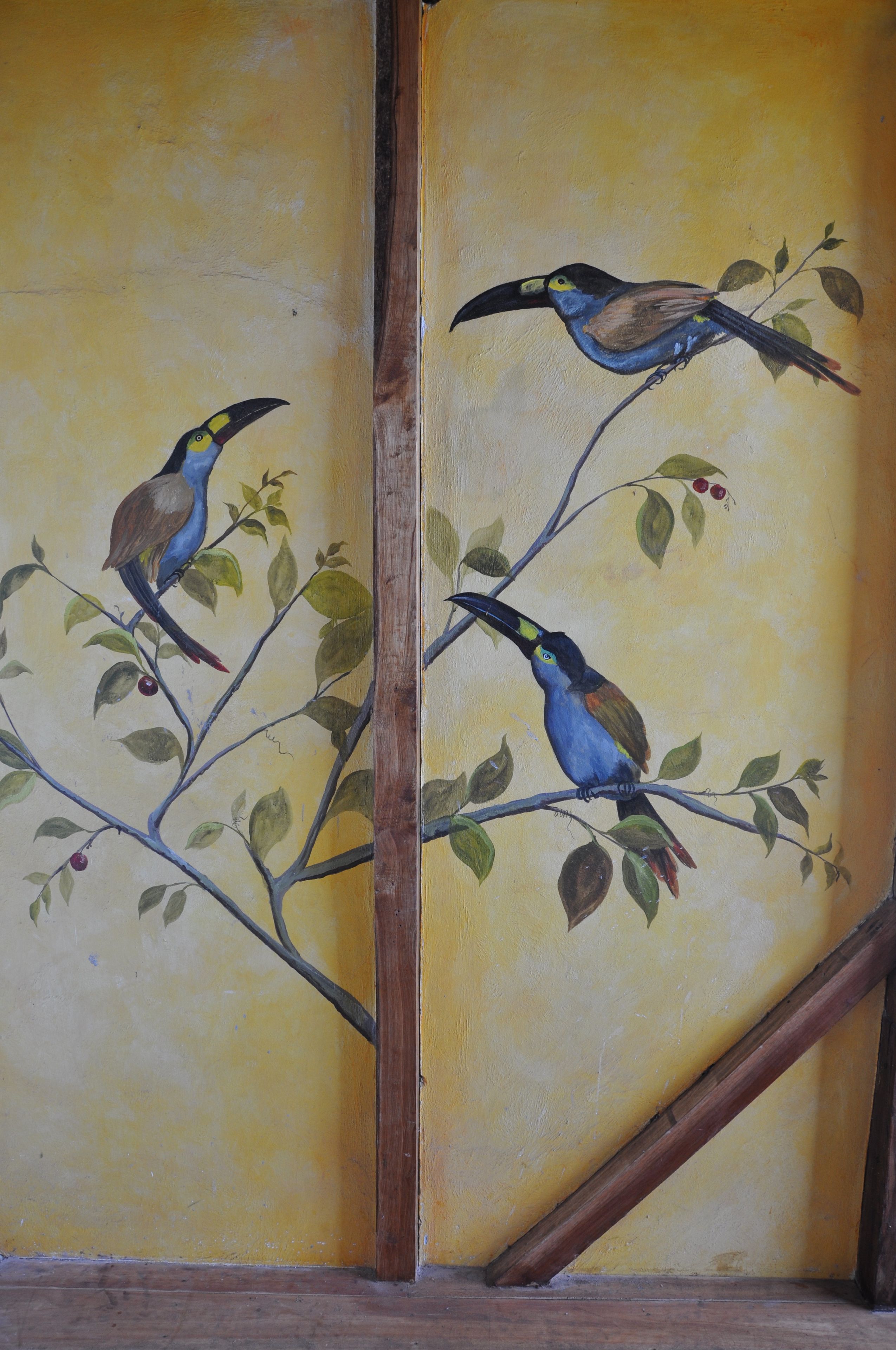 Un mur orné d’une fresque représentant des oiseaux perchés sur des branches.