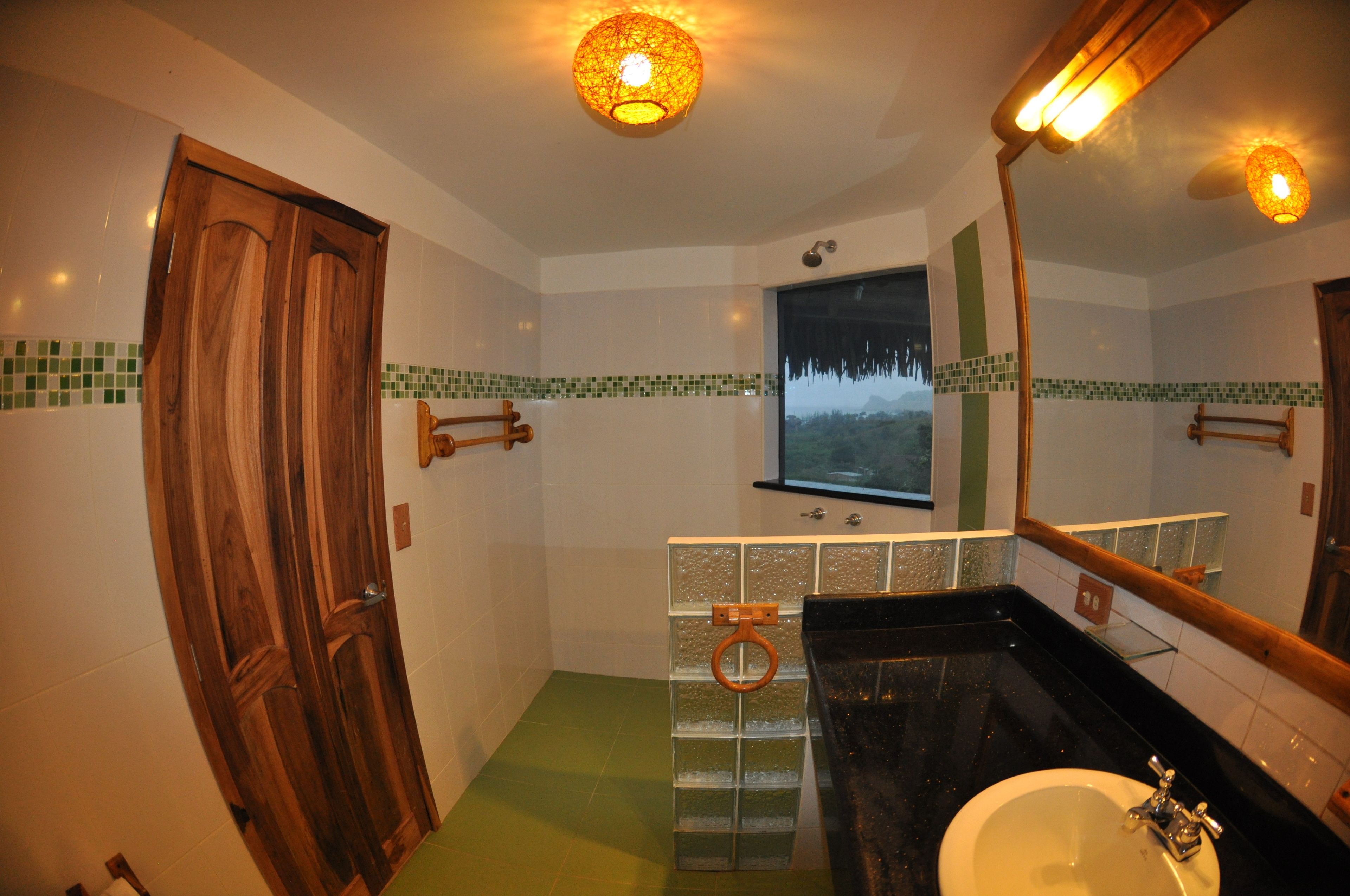 A bathroom with a wooden door, a glass shower enclosure, a sink, and a mirror.