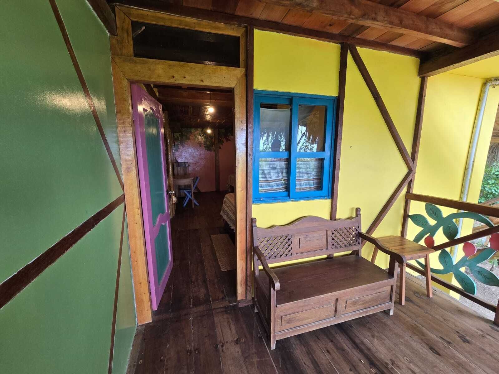 Un banc en bois doté d’un dossier à lattes et de tiroirs, placé sous une fenêtre ornée de bordures bleues.
