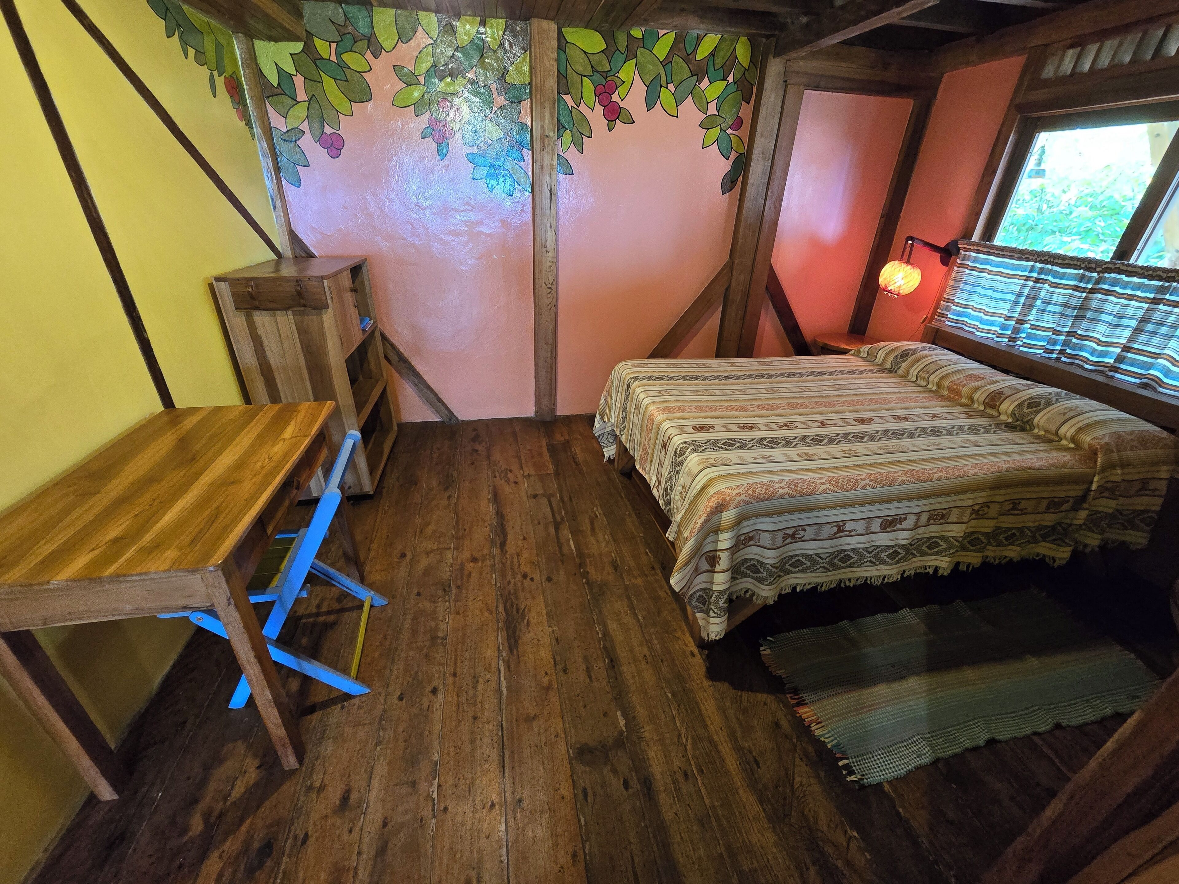 Una habitación con una cama de madera, una mesita de madera y un banco.