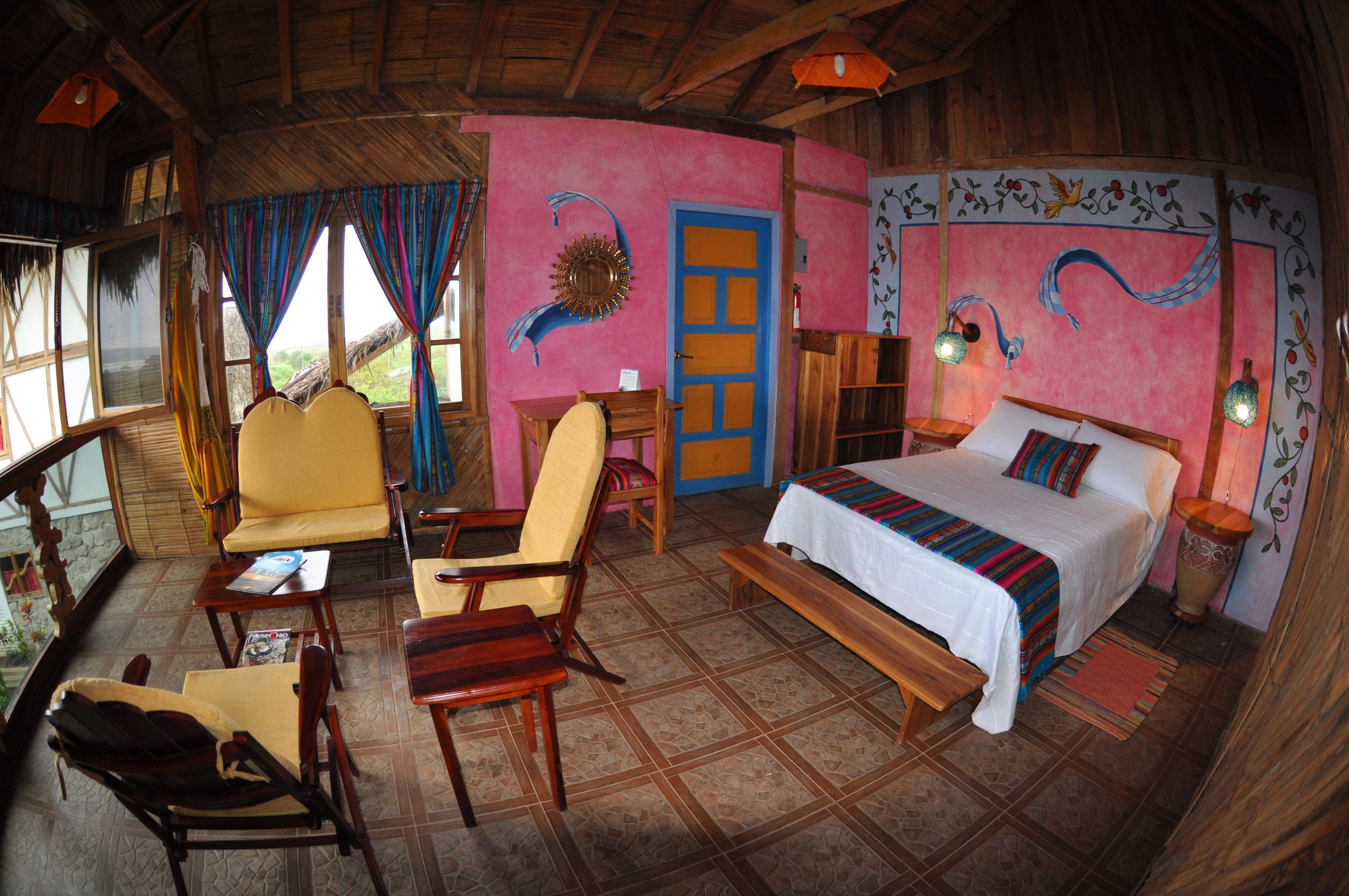 A room with a bed, two chairs, a small table, and a window with curtains.