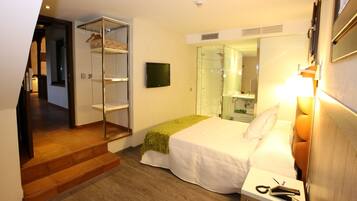 Una habitación de hotel con una cama, una mesita de noche, un espejo, un televisor y un armario con ropa colgada.