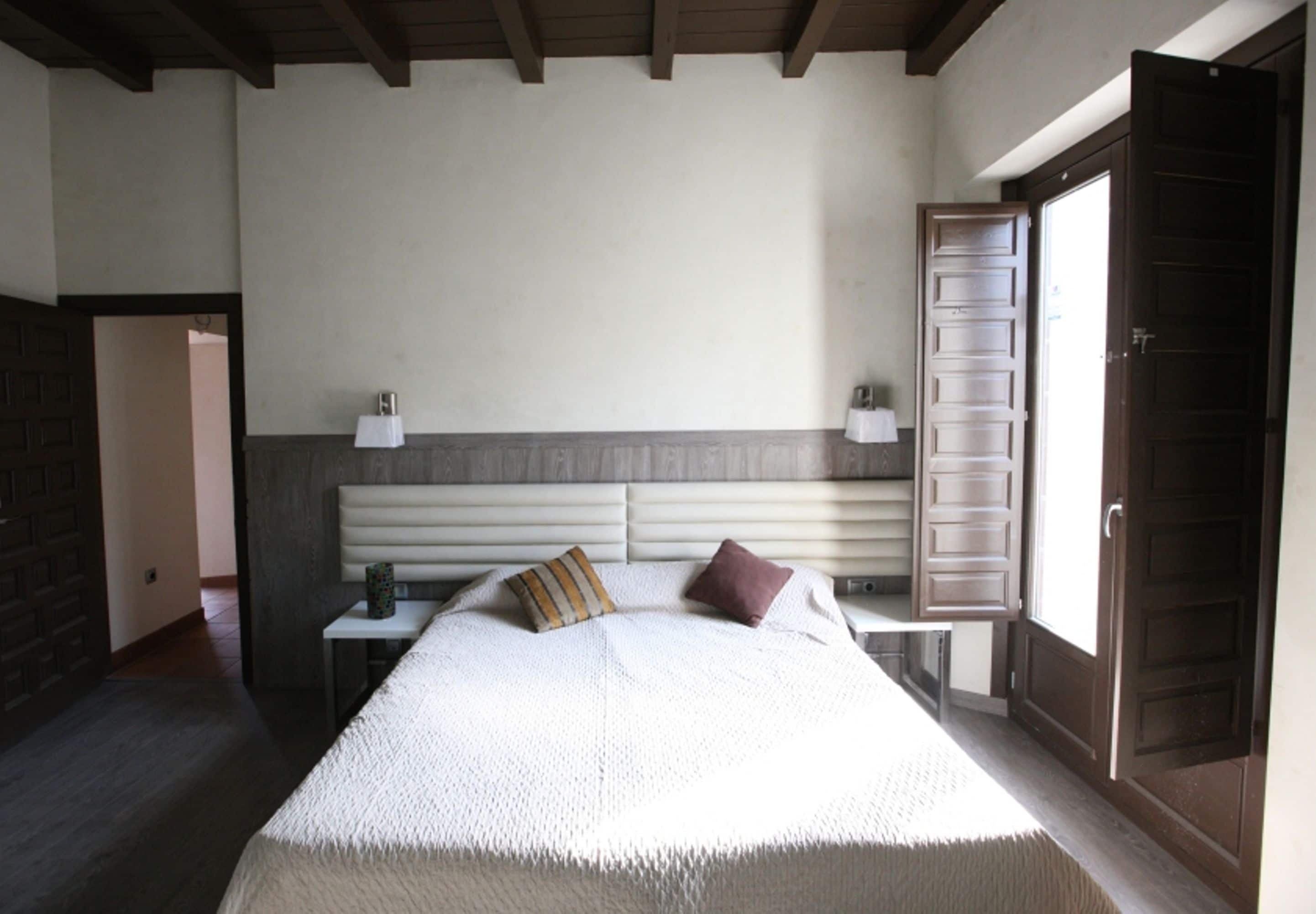 A bedroom with a bed, bedside tables, a nightstand, a lamp, and a door.