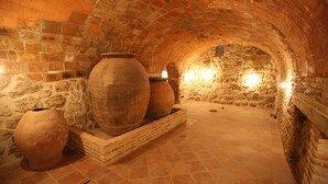 A stone-walled, vaulted room with large clay pots and a tiled floor. - Evenia Alcalá Boutique Hotel (Alcala de Henares)
