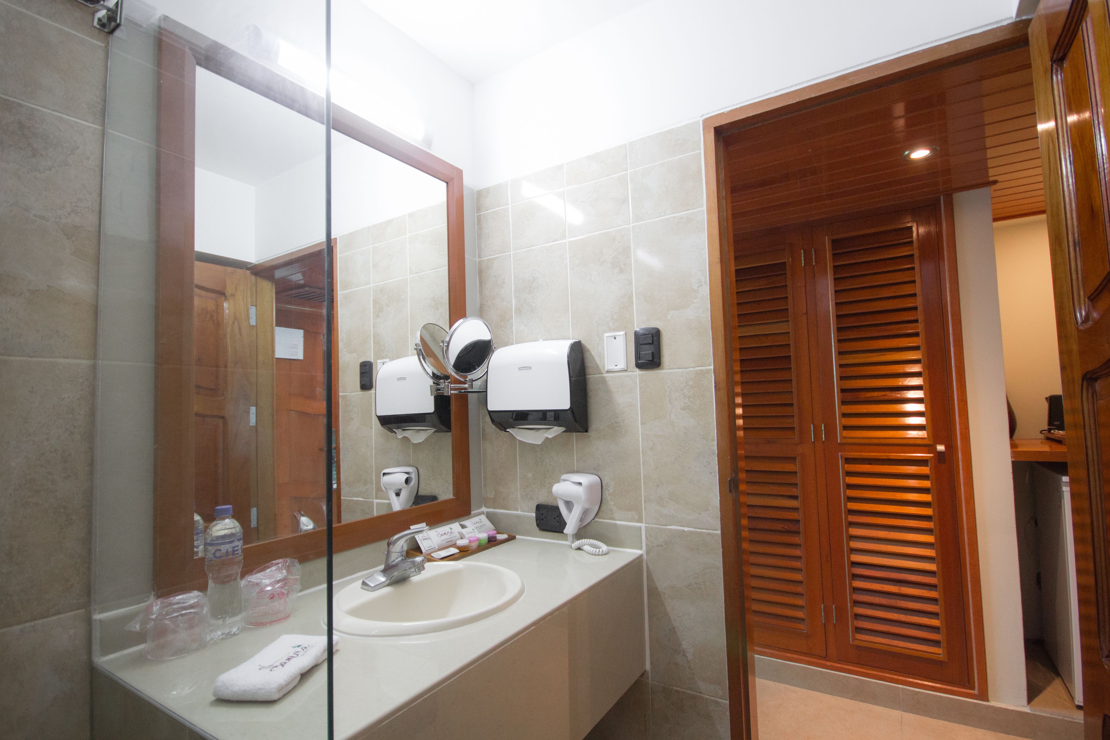 A modern bathroom with a large mirror, a sink, and a wooden door.